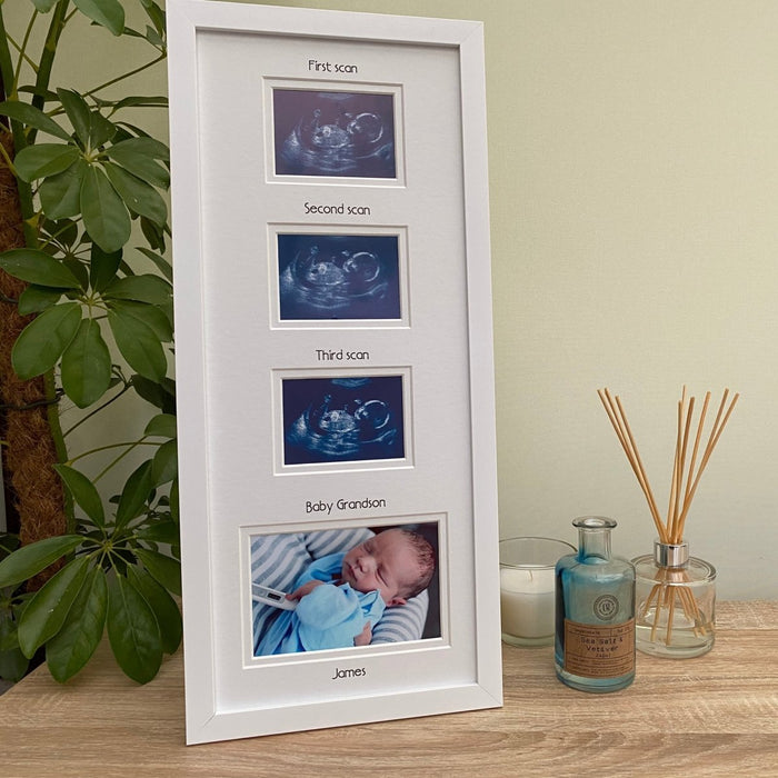 White collage baby scan picture frame standing on tabletop next to a white candle, diffuser and green plant