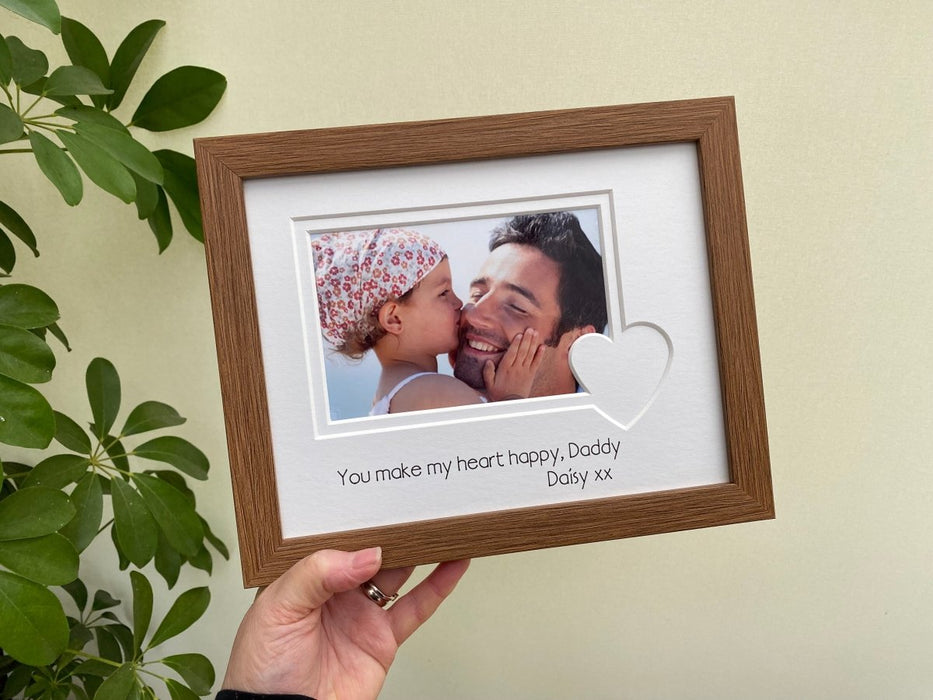 Holding up a dark brown wood-effect love heart picture frame